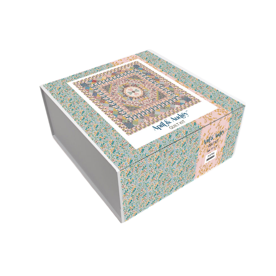 Quilt kit box with blue, pink, and cream patchwork fabric design on the lid.