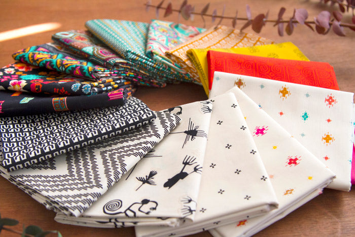 Stack of folded fabric squares with geometric and animal prints in mixed colors