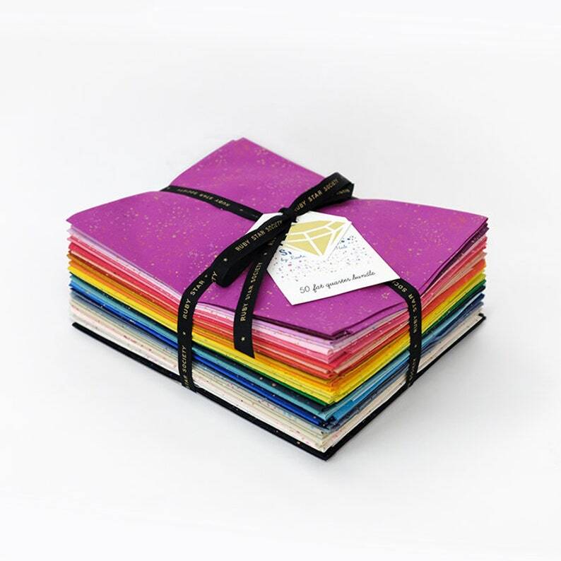 Speckled fat quarter bundle tied with ribbon, showing layered multicolor fabric squares