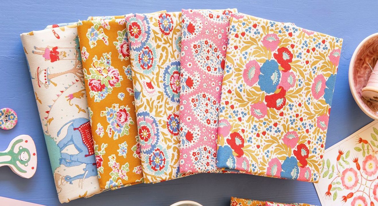 Floral fabric fat quarters laid out, mustard yellow, pink, blue, and white patterned prints