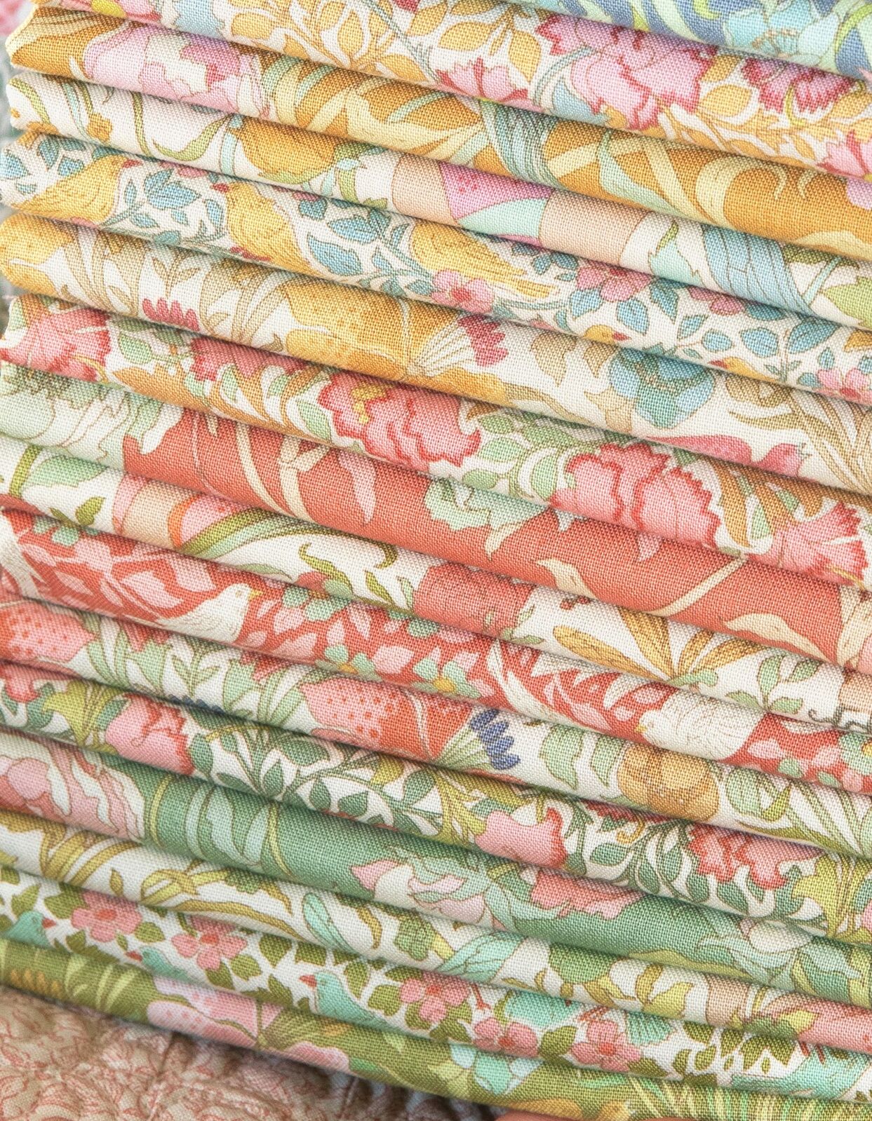 Stacked fabric squares with pastel bird and leaf floral patterns, folded layers
