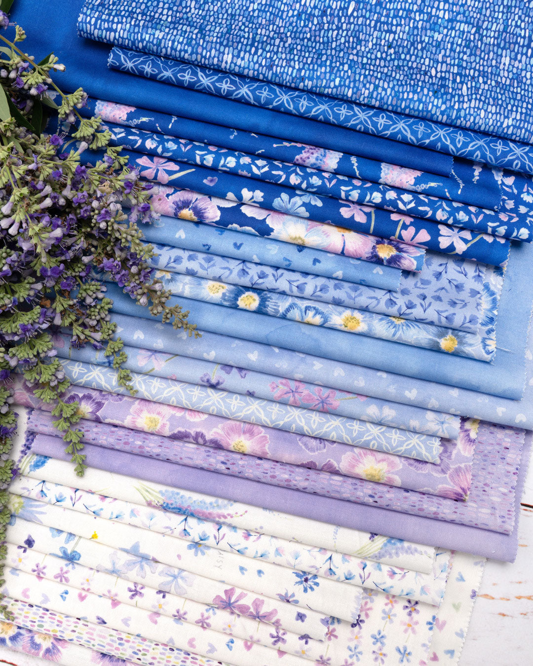Collection of floral-patterned fabric strips in various shades of blue and purple.