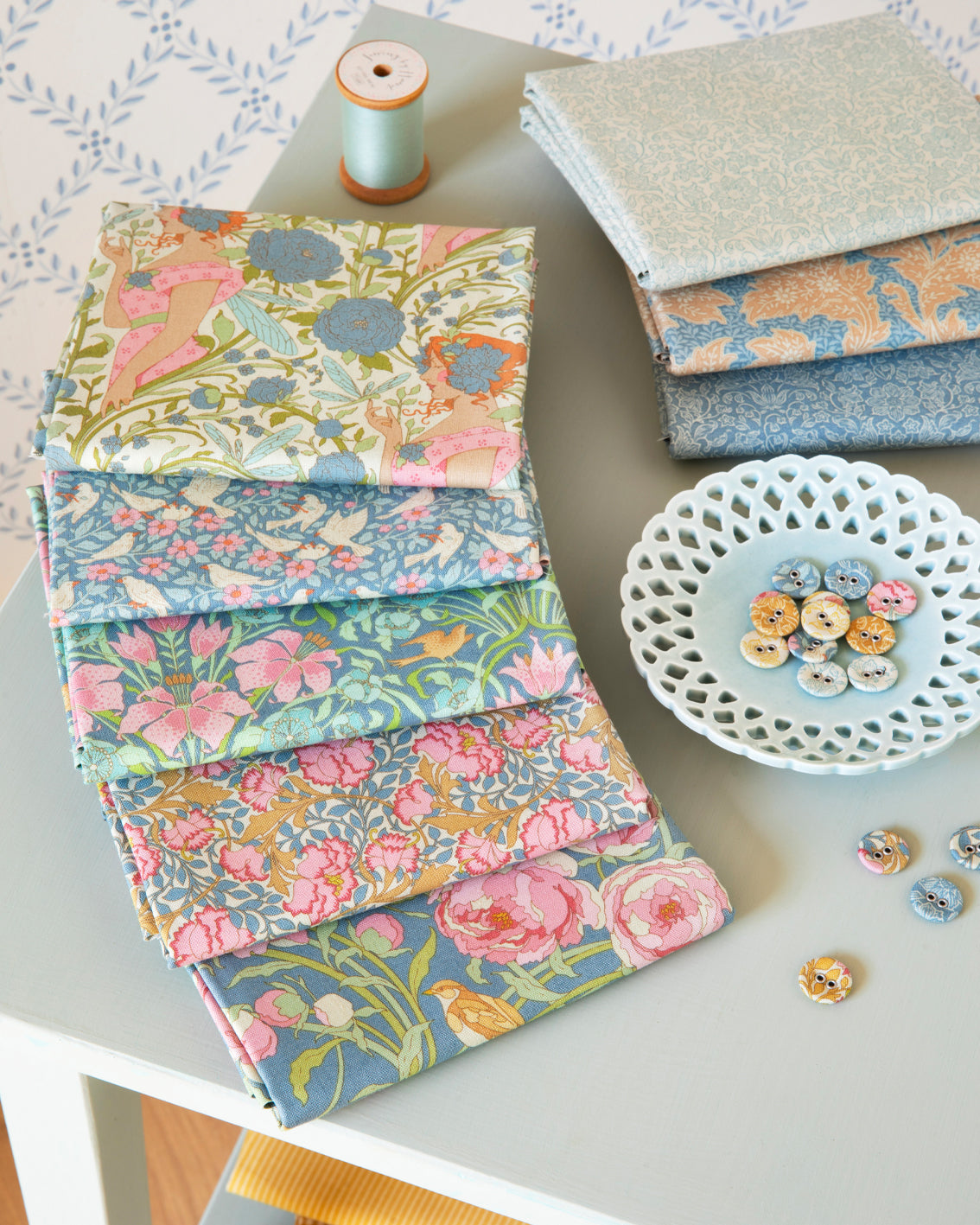 Stack of blue floral fat quarter fabric squares with coordinated multicolor prints