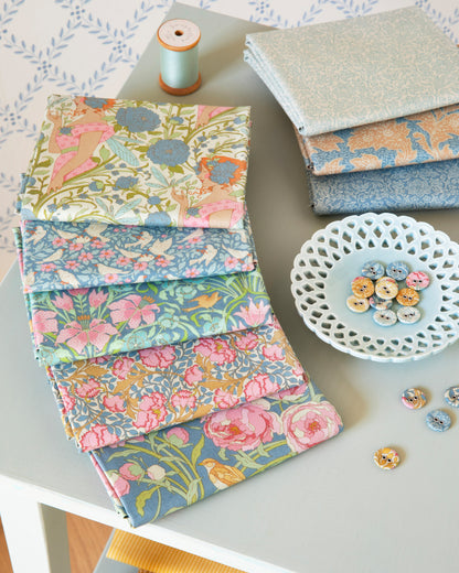 Stack of blue floral fat quarter fabric squares with coordinated multicolor prints