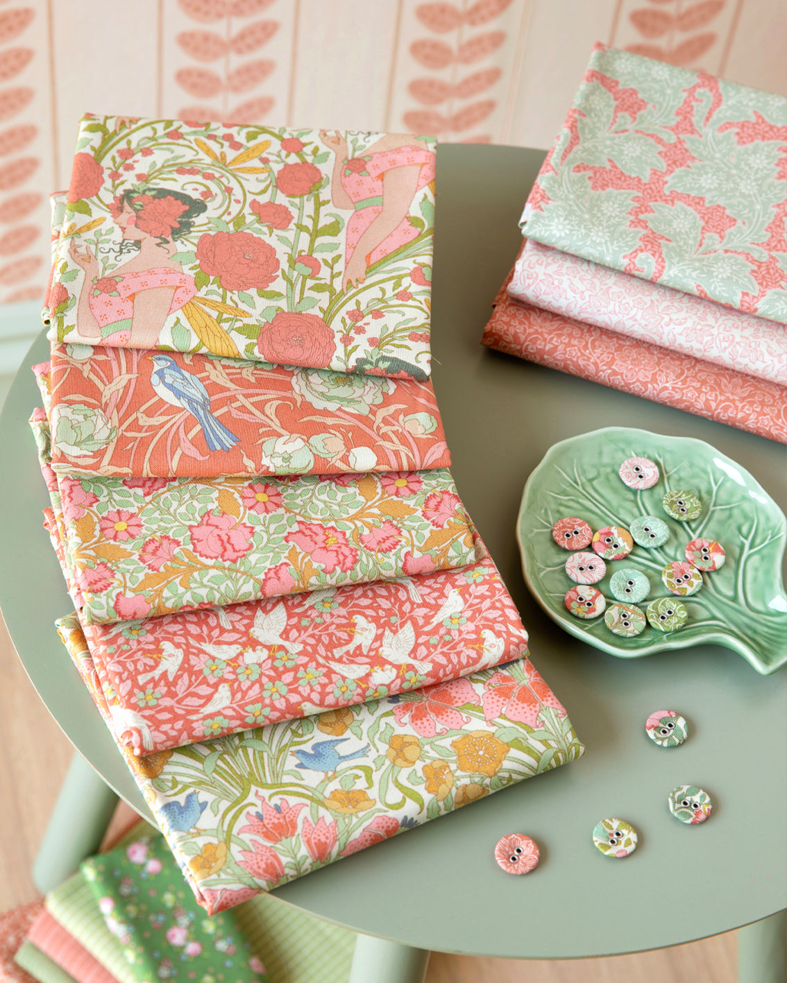 Assorted coral, green, and cream floral bird fat quarters stacked and folded