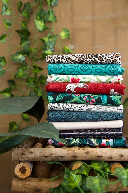 Stack of folded fat quarter fabrics in teal, red, floral, and leopard leaf prints