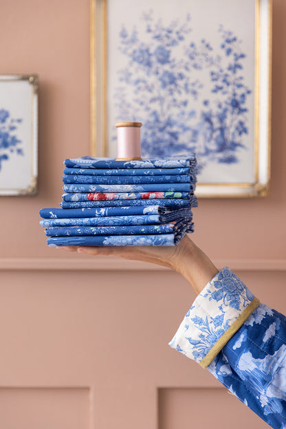 Stack of blue floral fat quarter fabrics with one piece held up