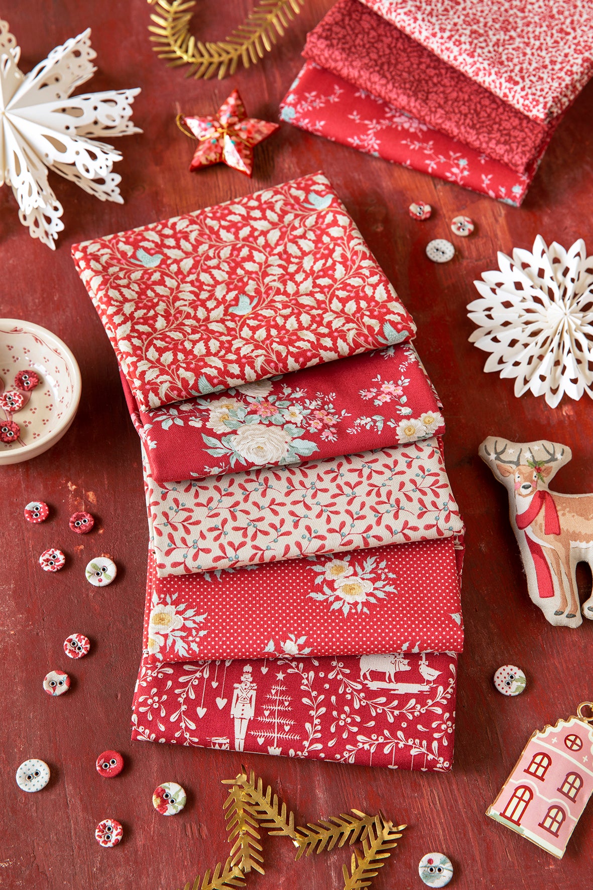 Stack of red holiday fat quarters with white floral and patterned designs