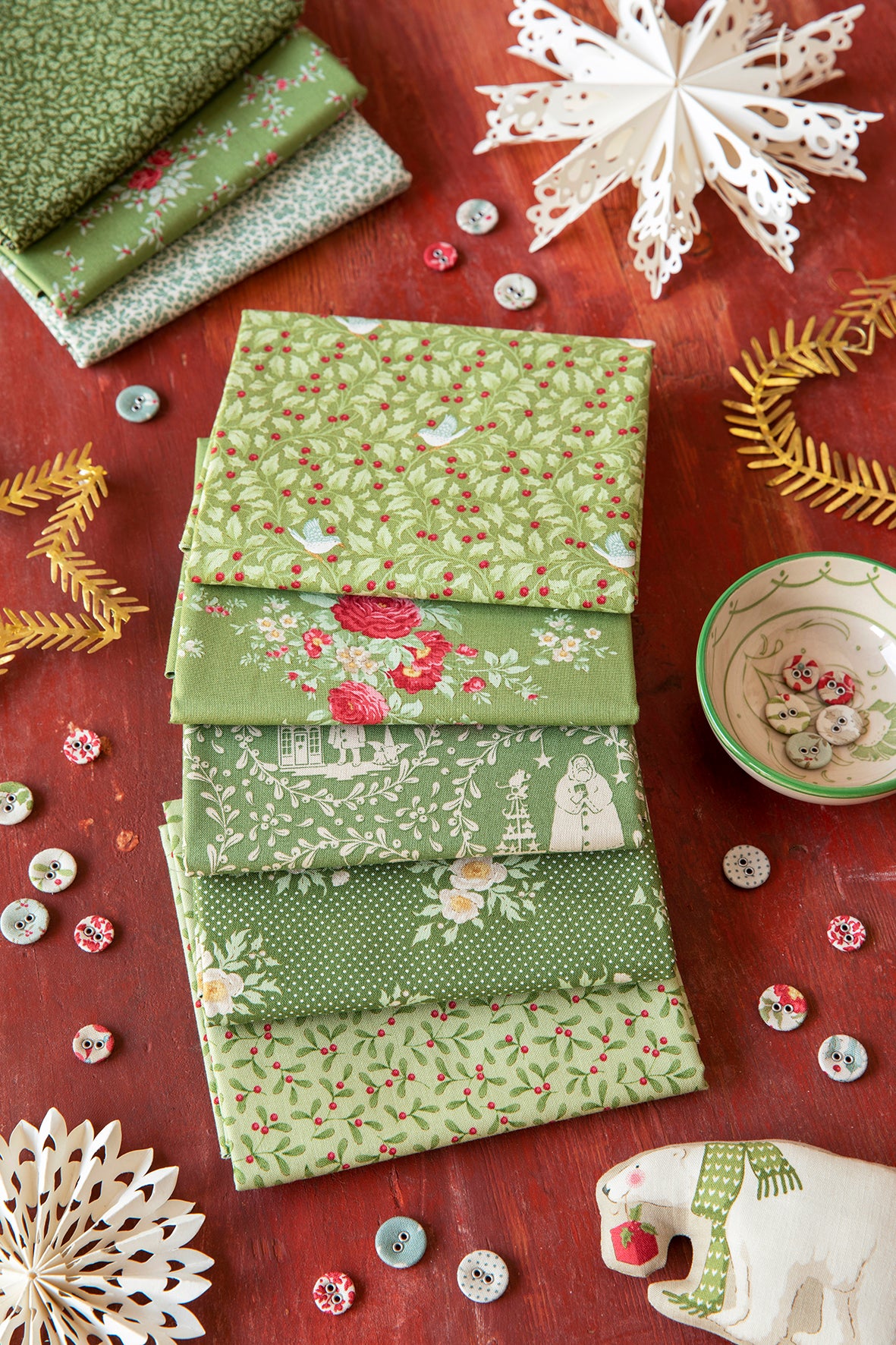 Folded green fat quarter fabric bundle with small red berries and floral motifs.