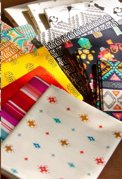 Fabric fat quarter bundle with tribal patterns and bright solids, neatly stacked squares