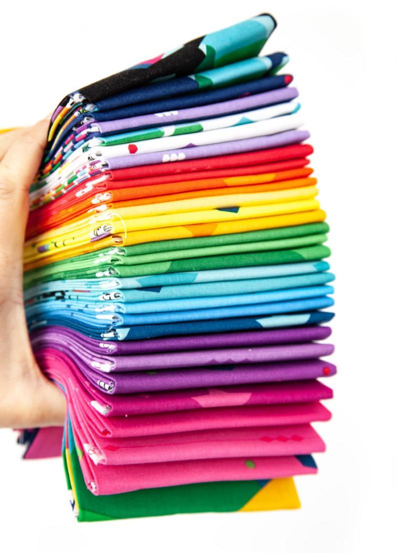Stack of colorful fabrics held by a hand on a white background