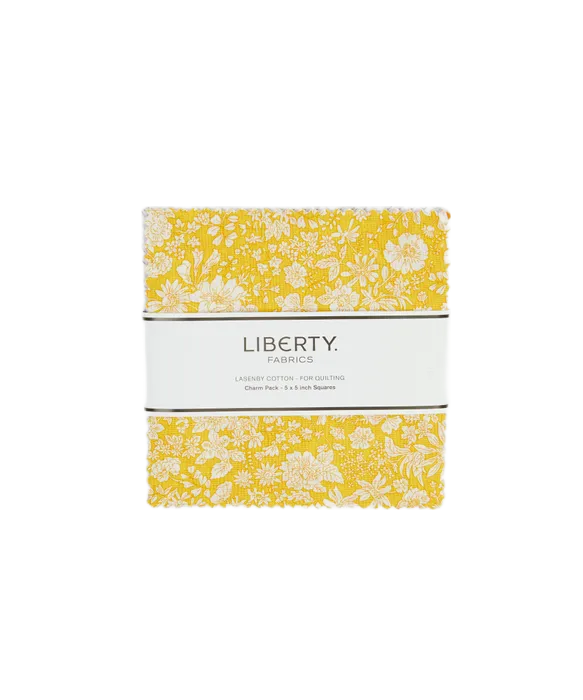 A charm square pack of Liberty Fabrics cotton piecing fabrics with a yellow and white floral pattern, wrapped in a white paper band labeled 'LIBERTY FABRICS'.