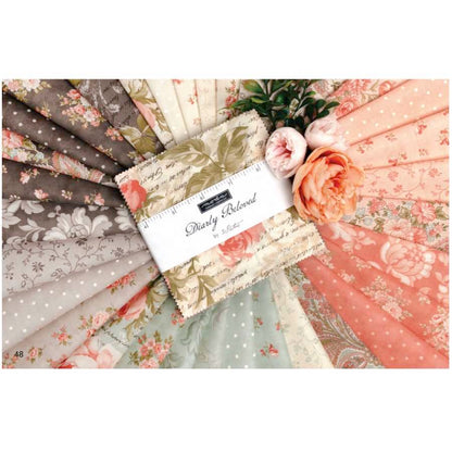 Floral quilt fabric bundle with stitched tag; peach, pink, gray prints in fabric squares