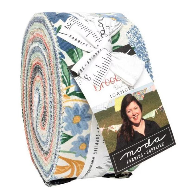 Rolled jelly roll bundle of floral fabric strips with paper product tags and ruler
