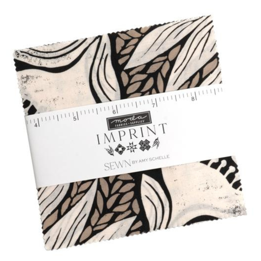 A charm square pack wrapped with a white paper band labeled 'imprint' and 'SEWN BY AMY SCHELLE', featuring a black, beige, and off-white abstract botanical pattern.