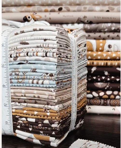 Stack of safari fat quarters with folded prints, animal motifs, and ruler details in neutrals