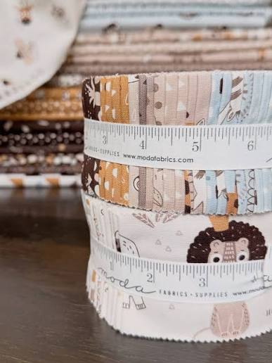 Safari fabric jelly roll bundle with measurement tape, tan, blue, and brown prints