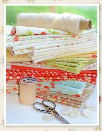 Stacked floral fabric bundles in soft reds, greens, and yellows, with charm squares