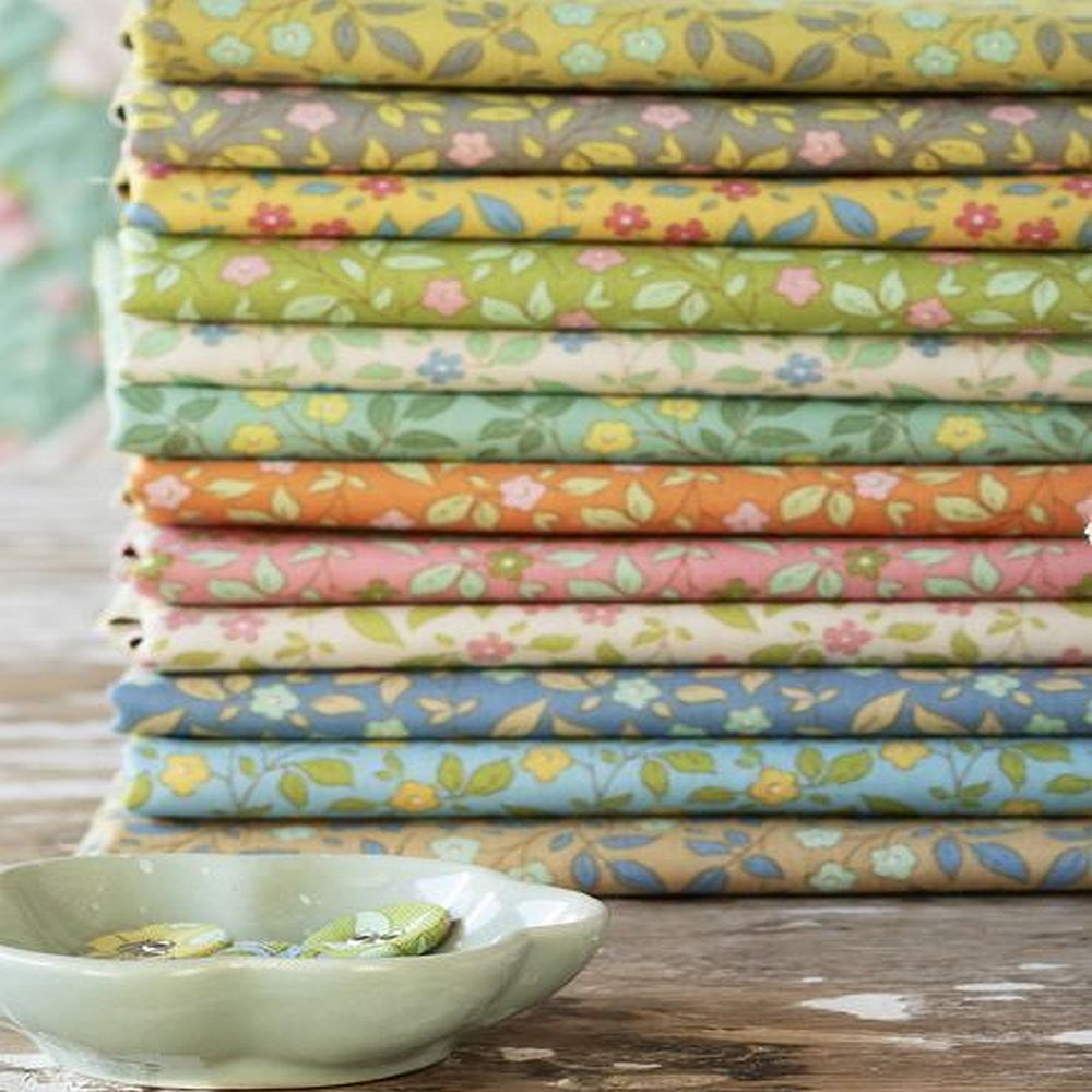 Stacked floral fabric fat quarters in pastel green, blue, pink, and orange