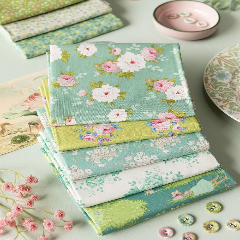 Stack of floral cotton fat quarters with roses on mint and pale green prints